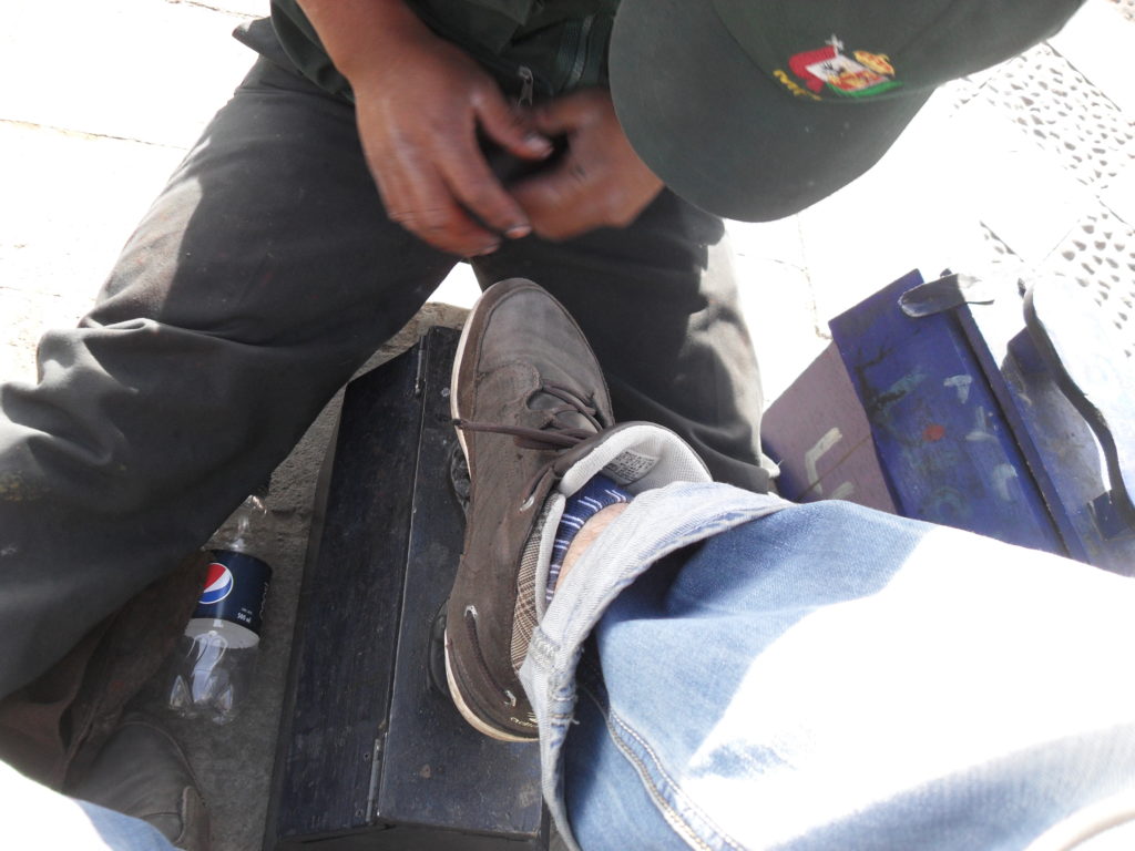 Ein junger Mann putzt mir an der Plaza de Armas von Cajamarca für 5 Soles die Schuhe 